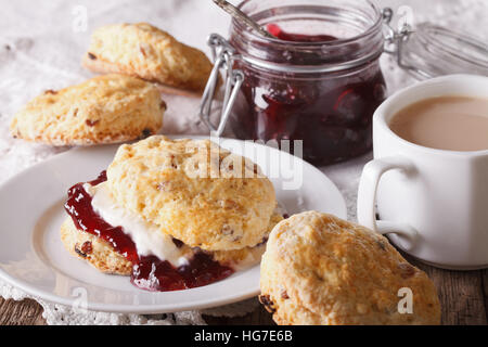 Inglese deliziosi scones con marmellata e tè con latte vicino sul tavolo. Posizione orizzontale Foto Stock