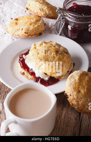 Pasticceria inglese: scones con marmellata e tè con latte vicino sul piano verticale. Foto Stock