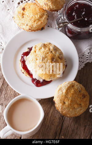 Inglese deliziosi scones con marmellata e tè con latte vicino sul piano verticale. Foto Stock