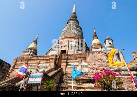 Statua di Buddha in corrispondenza del fondo di un antico e grande pagoda in cielo blu sullo sfondo di Wat Yai Chai Mongkon tempio di Phra Nakhon Si Ayutthaya storico Foto Stock