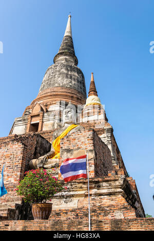 Statua di Buddha in corrispondenza del fondo di un antico e grande pagoda in cielo blu sullo sfondo di Wat Yai Chai Mongkon tempio di Phra Nakhon Si Ayutthaya storico Foto Stock