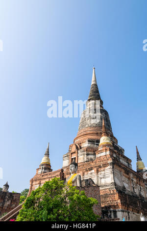 Statua di Buddha in corrispondenza del fondo di un antico e grande pagoda in cielo blu sullo sfondo di Wat Yai Chai Mongkon tempio di Phra Nakhon Si Ayutthaya storico Foto Stock