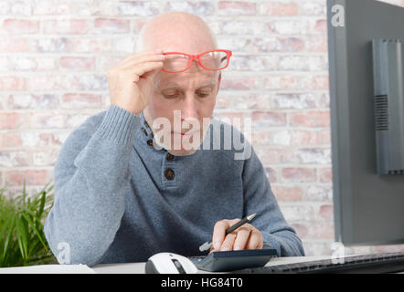 Imprenditore maturo avendo problemi di vista, egli sta utilizzando la calcolatrice Foto Stock