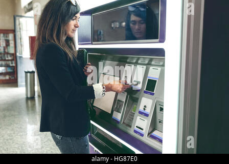 Donna l'inserimento della carta nella macchina ATM Foto Stock