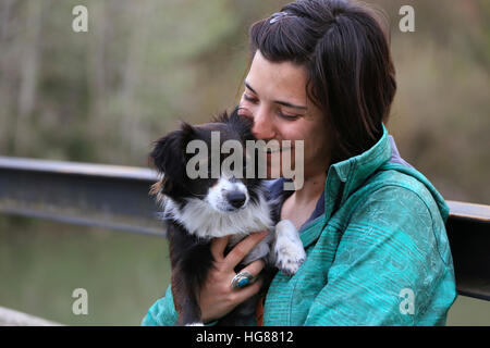 Donna felice abbracciando Border Collie mentre è seduto su un banco di lavoro in posizione di parcheggio Foto Stock