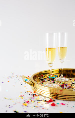Champagne flauti nel vassoio con i confetti sul tavolo contro uno sfondo bianco Foto Stock