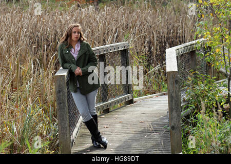 Giovane donna appoggiata sul ponte in autunno Foto Stock