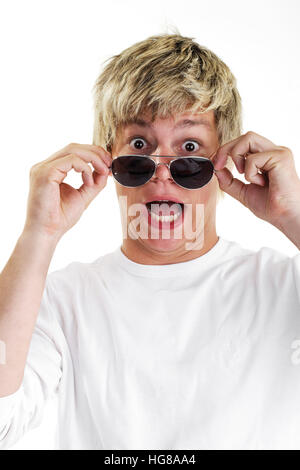 Giovane uomo che guarda oltre i suoi occhiali da sole, stupito Foto Stock