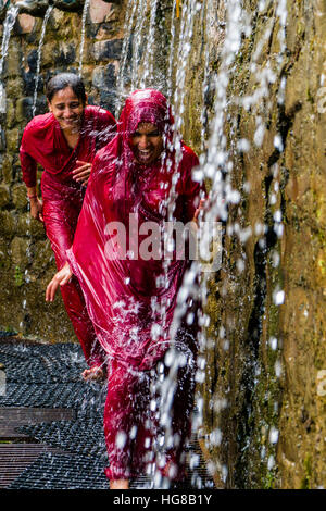 Due pellegrini femmina in esecuzione attraverso la 108 pozzi sacri, sotto la doccia per purificare il corpo e anima, Muktinath, Mustang District Foto Stock