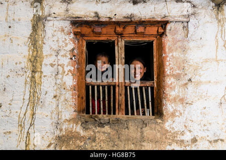 Giovane donna e figlio guardando fuori della finestra agriturismo, Purang, Mustang District, Nepal Foto Stock