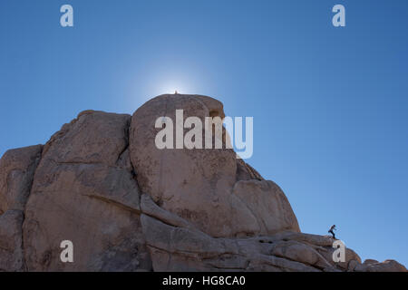 Vista in lontananza persone arrampicate su roccia contro il cielo blu chiaro Foto Stock