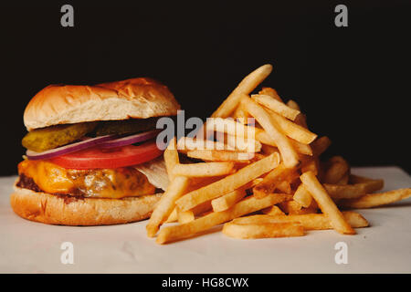 Close-up di hamburger con patatine fritte sul tavolo su sfondo nero Foto Stock