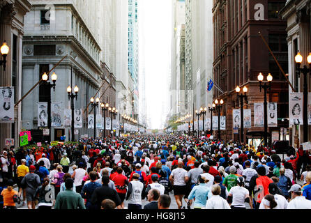 Grande gruppo di maratona per chi ama fare jogging in esecuzione attraverso la strada di città con edifici alti. Foto Stock