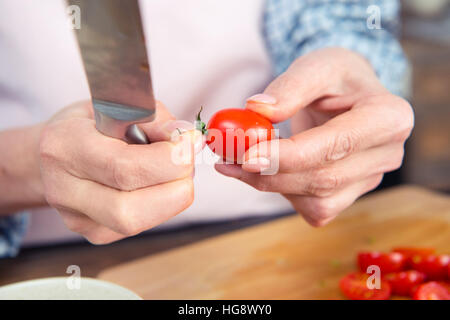 Close-up vista parziale della donna che mantiene il coltello e il pomodoro Foto Stock