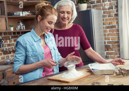 Nonna e nipote setacciare la farina per i cookie in cucina Foto Stock