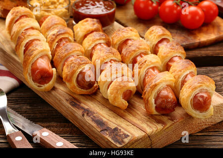 Laminati di hot dog salsicce cotto in pasta sfoglia su sfondo di legno Foto Stock