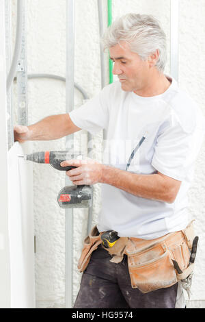 Builder foro di perforazione nella parete Foto Stock