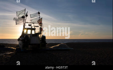 Una barca da pesca stagliano contro il sorgere del sole sulla spiaggia di mattina presto a Aldeburgh Suffolk in Inghilterra Foto Stock