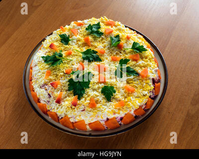 Aringa sotto una pelliccia, un insalata di aringhe salate filetto, patate bollite, barbabietole, carote, cipolle fresche e la maionese su una piastra Foto Stock