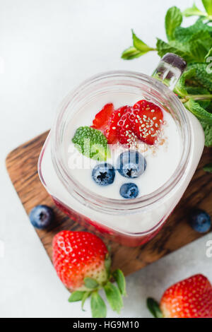 Frullato di fragola e rabboccato con fragole, mirtilli, chia semi e foglie di menta servito in tazza di vetro Foto Stock