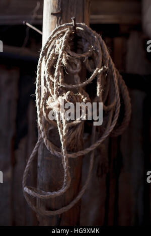 Corda intrecciata appesi ad un palo di legno nel fienile Foto Stock