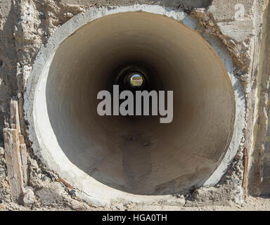 Vista attraverso una concreta della tubazione di drenaggio canale sotterraneo sotto una strada nel deserto Foto Stock