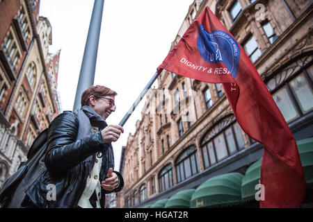 Londra, Regno Unito. Il 7 gennaio, 2017. Un sostenitore del Regno voci del commercio mondiale unione detiene il sindacato la bandiera a una protesta al di fuori di Harrods contro il negozio di ritenzione fino a 75% del 12,5% di tassa di servizio aggiunto per le fatture di diners nei suoi ristoranti di lusso. Credito: Mark Kerrison/Alamy Live News Foto Stock