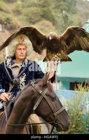 Trainer professionale a cavallo e Golden Eagle con ali spiegate a Sunkar Raptor Centre Almaty Kazakhstan Foto Stock