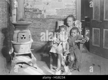 La madre ed i suoi due bambini seduti dalla stufa a legna, 1937. Foto Stock