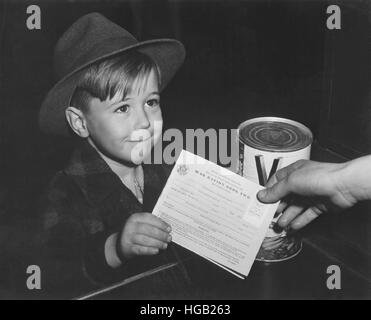 Un ansioso ragazzo scuola ottiene la sua prima esperienza di utilizzo di razione di guerra di prenotare due. circa 1943 Foto Stock