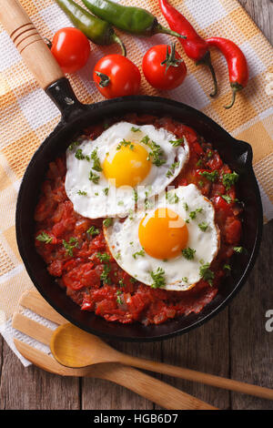 Huevos rancheros closeup in padella e gli ingredienti sul tavolo, verticale vista da sopra Foto Stock