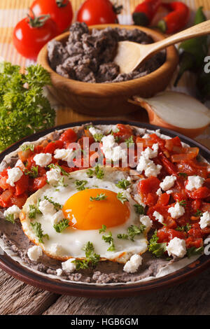 Mexican uova fritte huevos rancheros e gli ingredienti da vicino sul piano verticale. Foto Stock