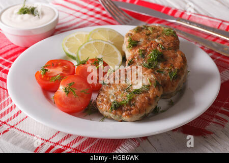 Pesce caldo torte con aneto close-up su una piastra bianca e salsa orizzontale. Foto Stock