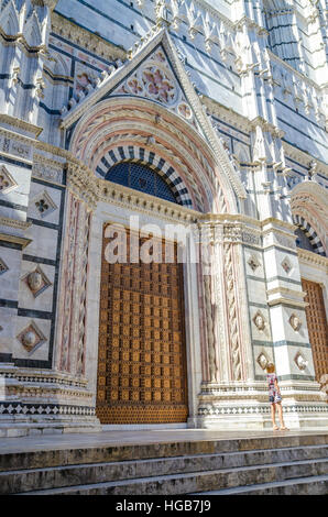 Porta di marmo bellissimo Duomo o chiesa con la giovane donna in abiti estivi, Siena, Italia, Europa Foto Stock
