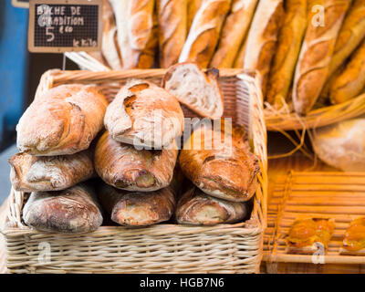 Baguette Rustico in vendita. Un cestello di baguettes rustico in vendita nel mercato Ambroise. Più il pane in un altro cestello ulteriormente all'indietro. Ambroise mercato, Foto Stock