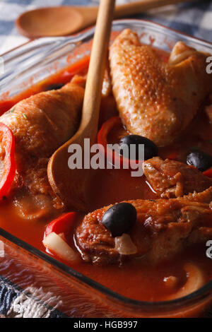 Stufato di pollo in salsa di pomodoro con verdure in una ciotola di vetro macro verticale. Foto Stock