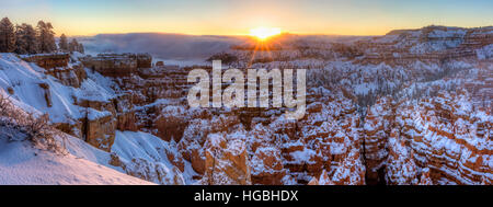 Il sole sorge su di un banco di nebbia sopra la città silenziosa di neve hoodoos protetti e punto al tramonto nel Parco Nazionale di Bryce Canyon, Utah Foto Stock