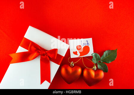Valentines confezione regalo con un fiocco rosso su sfondo rosso. Immagine del giorno di San Valentino. Foto Stock