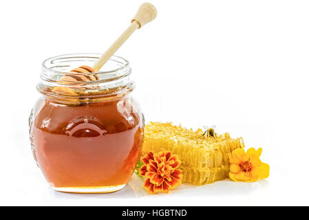 Vaso pieno di miele accanto al nido e bee e fiori su sfondo bianco Foto Stock