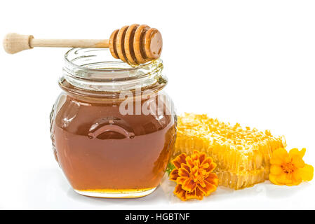 Vaso pieno di miele accanto al nido e fiori su sfondo bianco Foto Stock