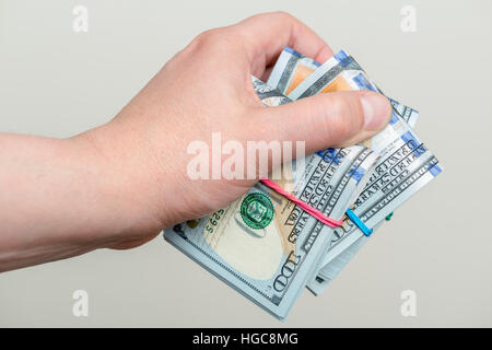 Maschio di mano azienda di confezioni di un centinaio di dollari di banconote Foto Stock