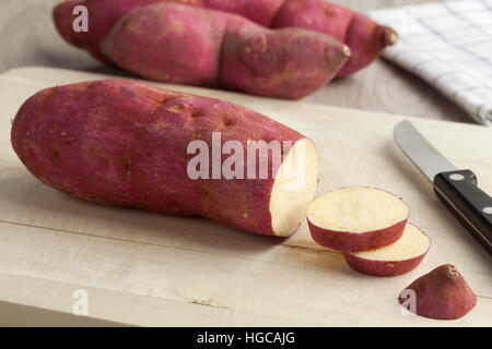 Viola le patate dolci con le fette su un tagliere Foto Stock