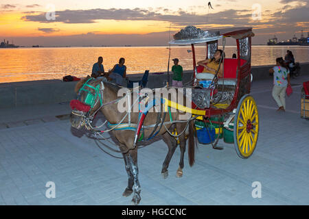 Kalesa alla Baia di Manila al tramonto, Filippine Foto Stock