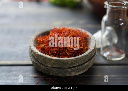 Materie organiche zafferano rosso Spice in un vaso di argilla su un tavolo di legno Foto Stock