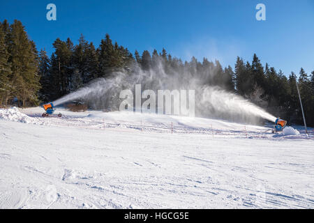 Lavorando cannoni da neve su una pista da sci Foto Stock