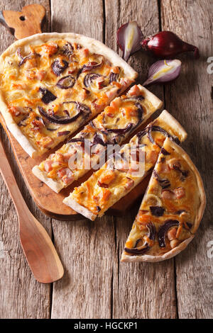 Una deliziosa torta a fette flammkuchen con la pancetta e la cipolla rossa close-up sul tavolo. In verticale Foto Stock