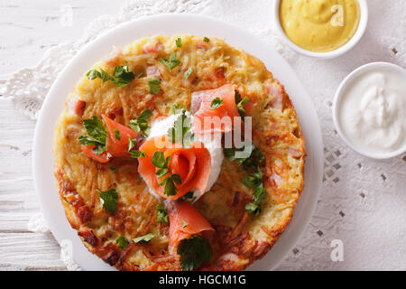 Frittelle di patate con salmone affumicato e salsa su una piastra di close-up. Orizzontale vista superiore Foto Stock