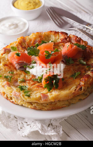 Deliziose frittelle di patate con salmone affumicato e salsa su una piastra di close-up. In verticale Foto Stock