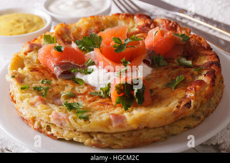 Deliziose frittelle di patate con salmone affumicato e salsa su una piastra di close-up orizzontale. Foto Stock