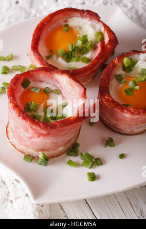 Uova fritte avvolto in pancetta su una piastra vicino sul piano verticale. Foto Stock